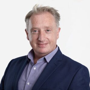 Andrew Longhurst, Managing Director, with short grey hair, smiling in a dark suit.