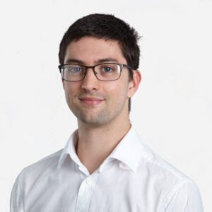 Adam Lewis, Principal Software Engineer, with short, dark brown hair and glasses, smiling in a white shirt.