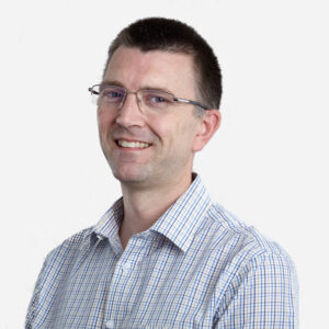 James Stanley, Engineering Manager, with short brown hair and glasses, smiling in a checked shirt.