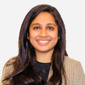 Sahana Gowda, Sales Executive, with long brown hair, smiling in a checked jacket.